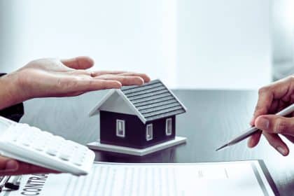 Une famille heureuse se tient devant une belle maison, symbole de leur projet immobilier sécurisé par une assurance emprunteur, véritable bouclier financier.