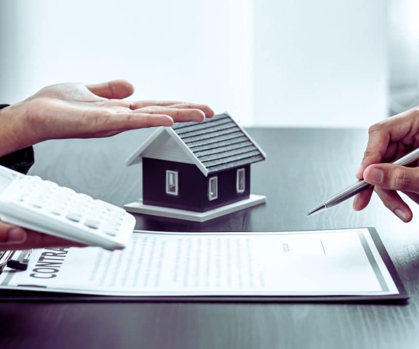 Une famille heureuse se tient devant une belle maison, symbole de leur projet immobilier sécurisé par une assurance emprunteur, véritable bouclier financier.